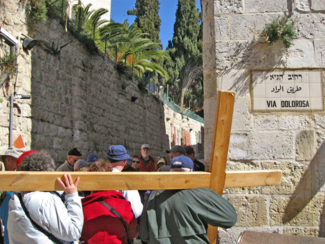 Pilgrims carrying the cross as they walk the Stations of the Cross Pilgrims carrying the cross as they walk the Stations of the Cross